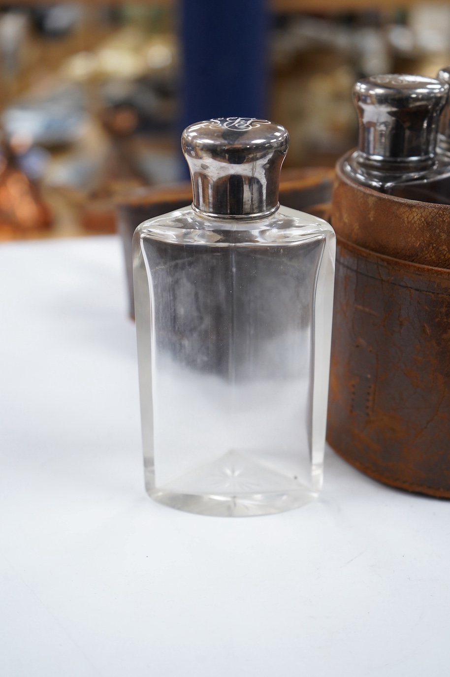 A cased set of four Edwardian silver mounted glass travelling scent bottles, with engraved monogram, George Bedingham, London, 1901, housed in a circular leather carrying case, bottles 14.5cm. Condition - fair to good an